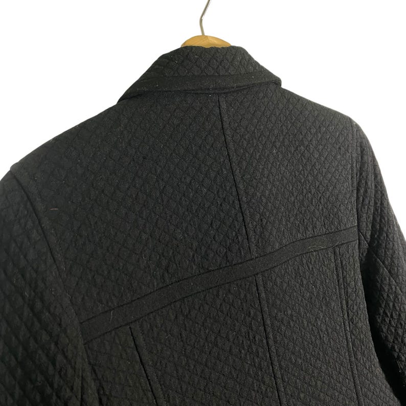 Puede incluir: Chaqueta acolchada negra con cuello y una costura en la espalda.
