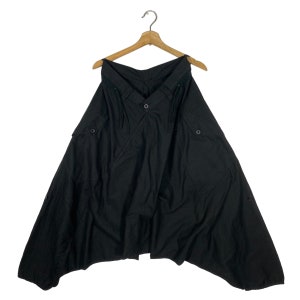 May include: Black cotton pants with a unique asymmetrical design, featuring a V-shaped neckline and two pockets on each side.