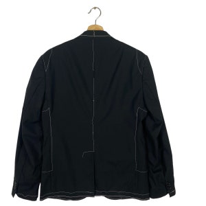 May include: A black blazer with white stitching detail. The blazer has a single button closure and long sleeves.