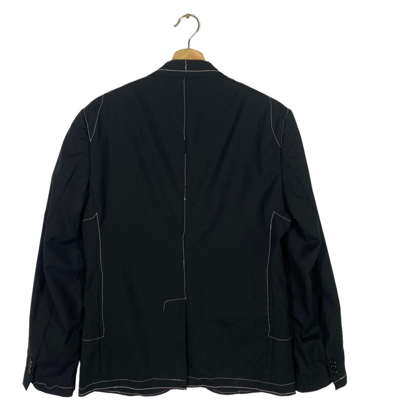 May include: A black blazer with white stitching detail. The blazer has a single button closure and long sleeves.