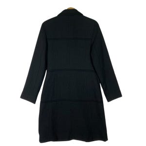 Puede incluir: Un abrigo acolchado negro con cuello y mangas largas. El abrigo tiene una silueta ajustada y un dobladillo recto.