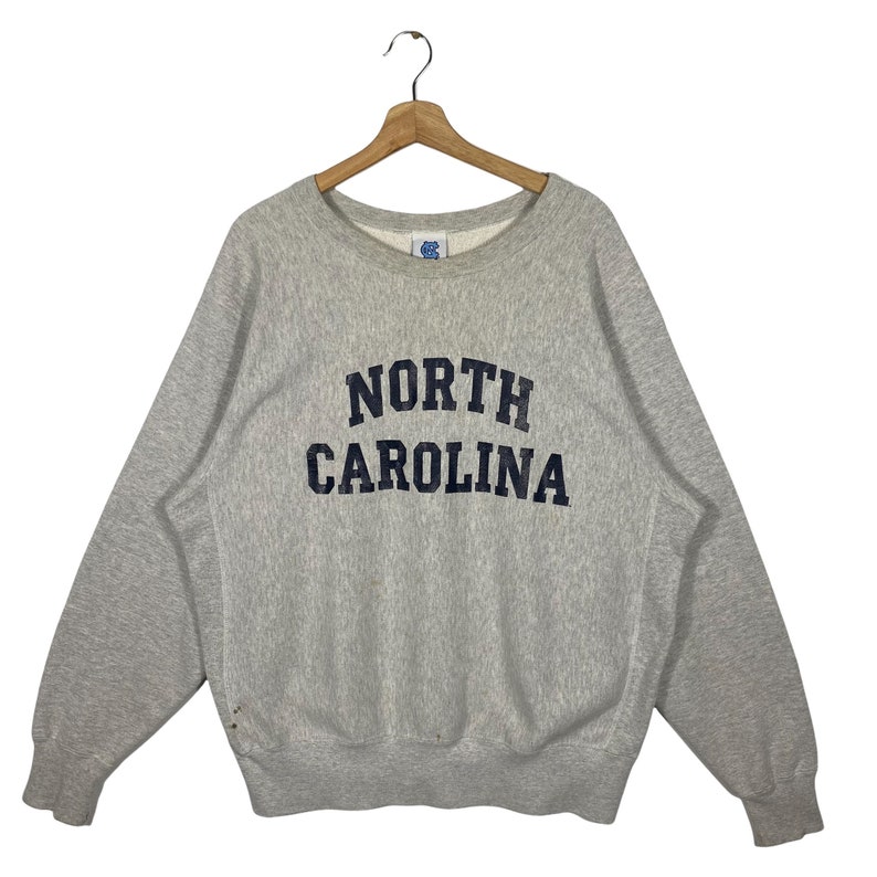 May include: A gray sweatshirt with the text "NORTH CAROLINA" in navy blue lettering.