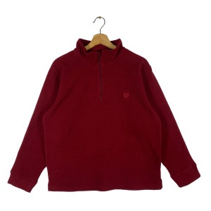 May include: A red fleece pullover with a half-zip closure and a small logo on the left chest.