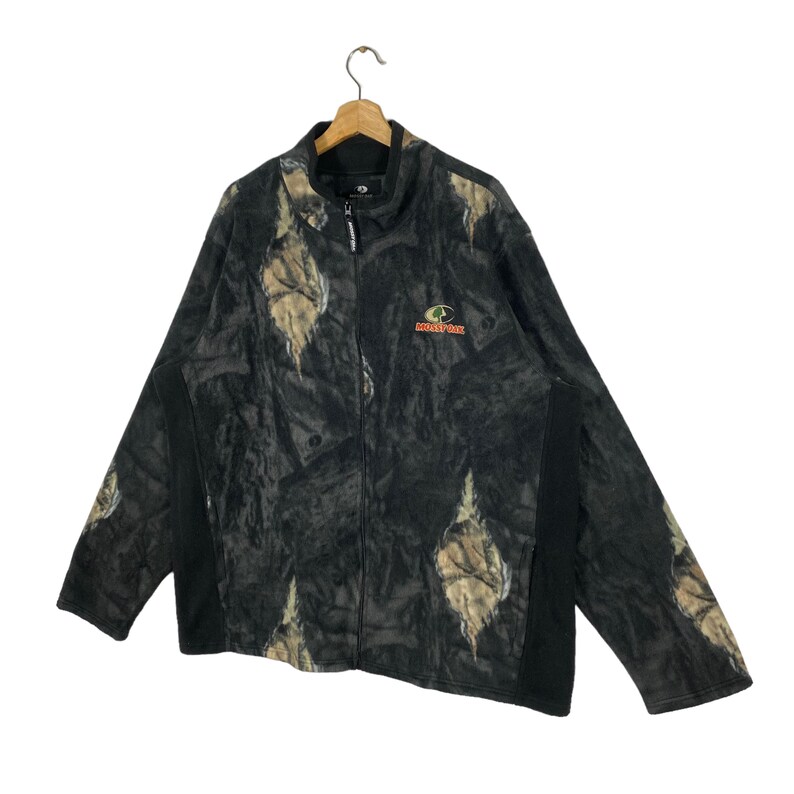 May include: A black and green camouflage fleece jacket with a zipper closure and a Mossy Oak logo on the front.