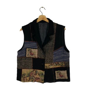 May include: A black vest with a patchwork design featuring various scenes and patterns. The vest has a collar and two buttons.