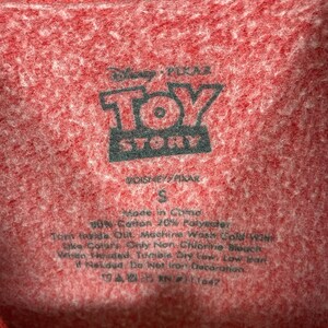 Puede incluir: Etiqueta de camiseta roja de Toy Story con el logotipo de Disney Pixar, talla S, hecha en China, 80% algod&oacute;n 20% poli&eacute;ster, instrucciones de cuidado: lavar a m&aacute;quina con agua fr&iacute;a, secar en secadora a baja temperatura, no planchar la decoraci&oacute;n.