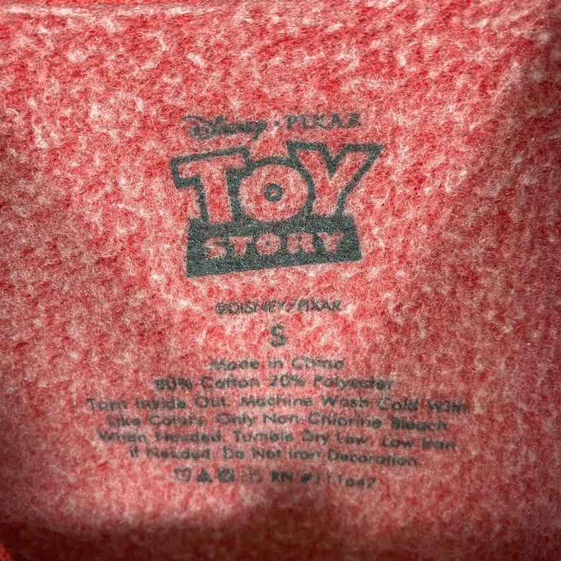 Puede incluir: Etiqueta de camiseta roja de Toy Story con el logotipo de Disney Pixar, talla S, hecha en China, 80% algod&oacute;n 20% poli&eacute;ster, instrucciones de cuidado: lavar a m&aacute;quina con agua fr&iacute;a, secar en secadora a baja temperatura, no planchar la decoraci&oacute;n.