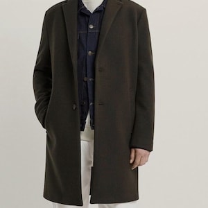 Pu&ograve; includere: Un cappotto lungo verde scuro a maniche lunghe con una chiusura a un solo bottone. Il cappotto ha una vestibilit&agrave; classica e aderente e una lunghezza leggermente pi&ugrave; lunga.