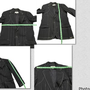May include: A black blazer with white stitching detail. The blazer has two pockets and a single button closure. The blazer is laid flat on a white surface.