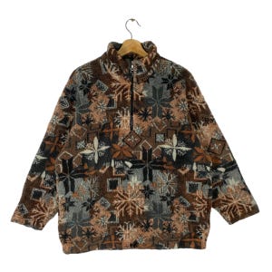 May include: A brown, gray, and white patterned fleece jacket with a zipper closure. The jacket has a snowflake design.