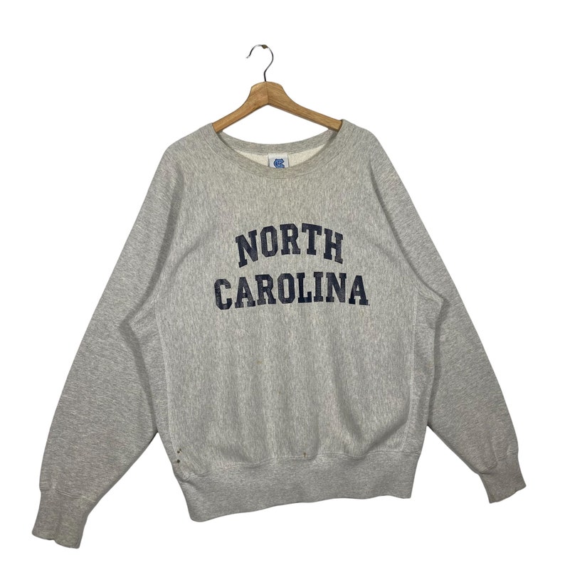 May include: A gray sweatshirt with the text "NORTH CAROLINA" in navy blue lettering.