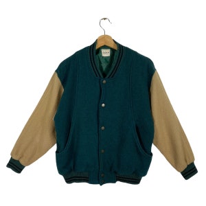 May include: A teal blue and brown varsity jacket with a button closure and black and white striped trim. The jacket has a label that says "Zara" on the inside.