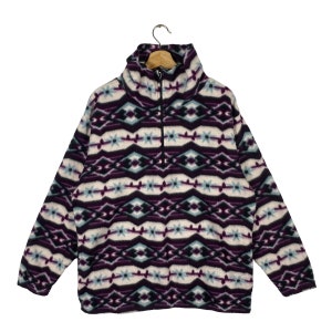Könnte beinhalten: Ein lila, blauer und weißer Fleece-Pullover mit einem Viertel-Reißverschluss.