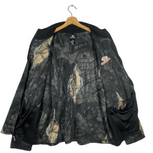 May include: Black and camouflage fleece jacket with a zipper closure and two pockets. The jacket has the words "MOssy OAK" printed on the front.