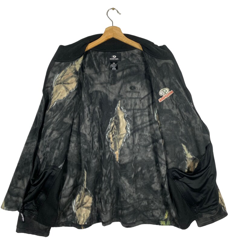 May include: Black and camouflage fleece jacket with a zipper closure and two pockets. The jacket has the words "MOssy OAK" printed on the front.