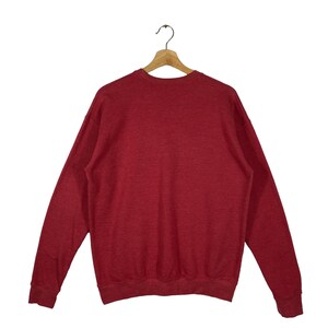 Puede incluir: Una sudadera roja de manga larga con cuello redondo.