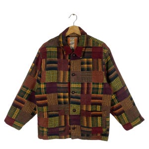 Puede incluir: Una chaqueta de patchwork con cierre de botones y mangas largas. La chaqueta está hecha de una variedad de telas a cuadros en tonos de rojo, marrón, amarillo y verde.