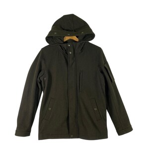 Peut inclure: Veste à capuche vert olive foncé avec une fermeture à boutons, deux poches avant et une petite poche sur la manche gauche. La veste a un design simple et classique et est faite d'un matériau doux et texturé. La capuche a une fermeture à bouton.