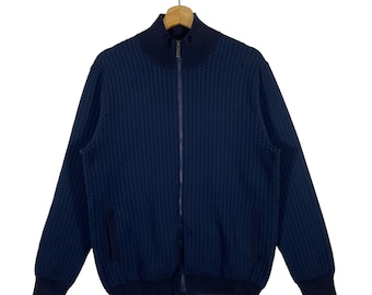 May include: A navy blue zip-up sweater with a waffle knit texture. The sweater has a high collar and two pockets.