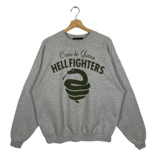 May include: Gray sweatshirt with a green snake graphic and the text "Croix de Guerre HELL FIGHTERS".
