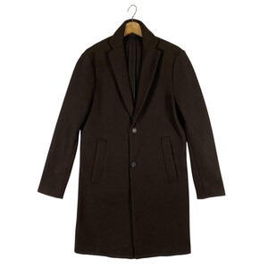 Pu&ograve; includere: Un cappotto lungo a maniche lunghe di colore marrone scuro con una chiusura a bottone singolo e due tasche. Il cappotto ha una vestibilit&agrave; classica e sartoriale.