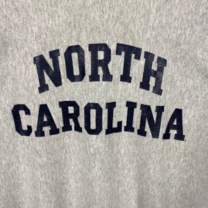 May include: Gray sweatshirt with "NORTH CAROLINA" printed in black letters.