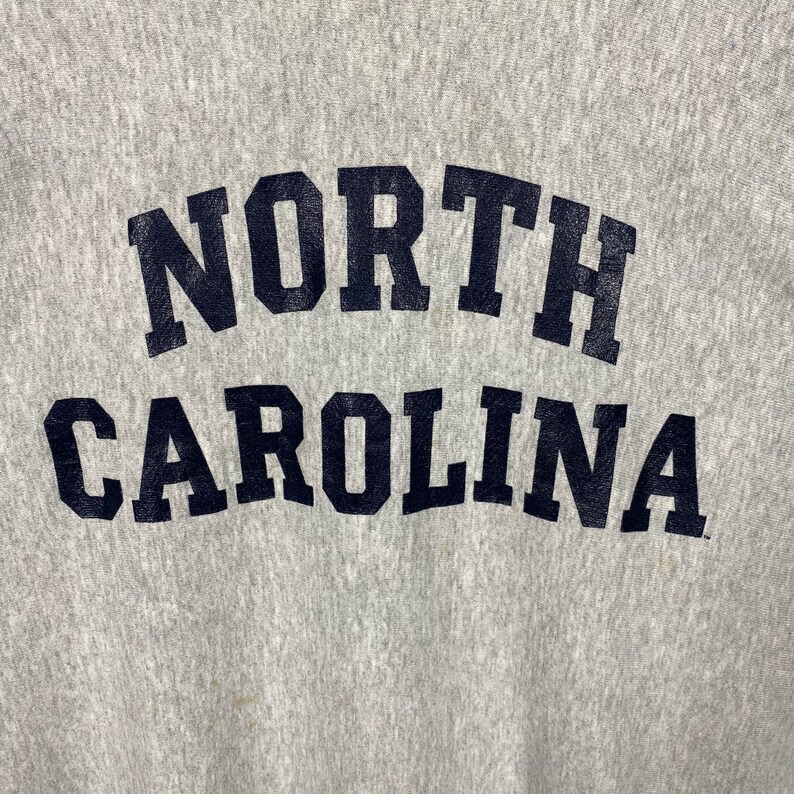 May include: Gray sweatshirt with "NORTH CAROLINA" printed in black letters.