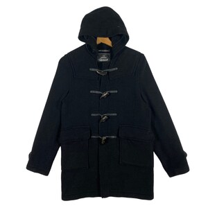 May include: A black hooded duffle coat with a toggle closure and two front pockets. The coat is made by the brand "The Authentic Duffle Coat Company".