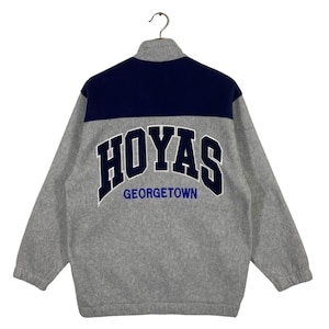 May include: A grey fleece jacket with a navy blue yoke and the words "Hoyas Georgetown" embroidered on the back.