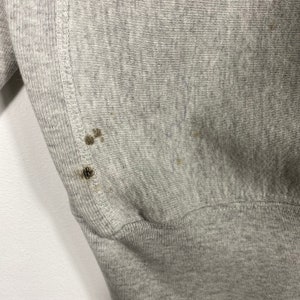 May include: Gray sweatshirt with a ribbed hem and a few small brown stains.