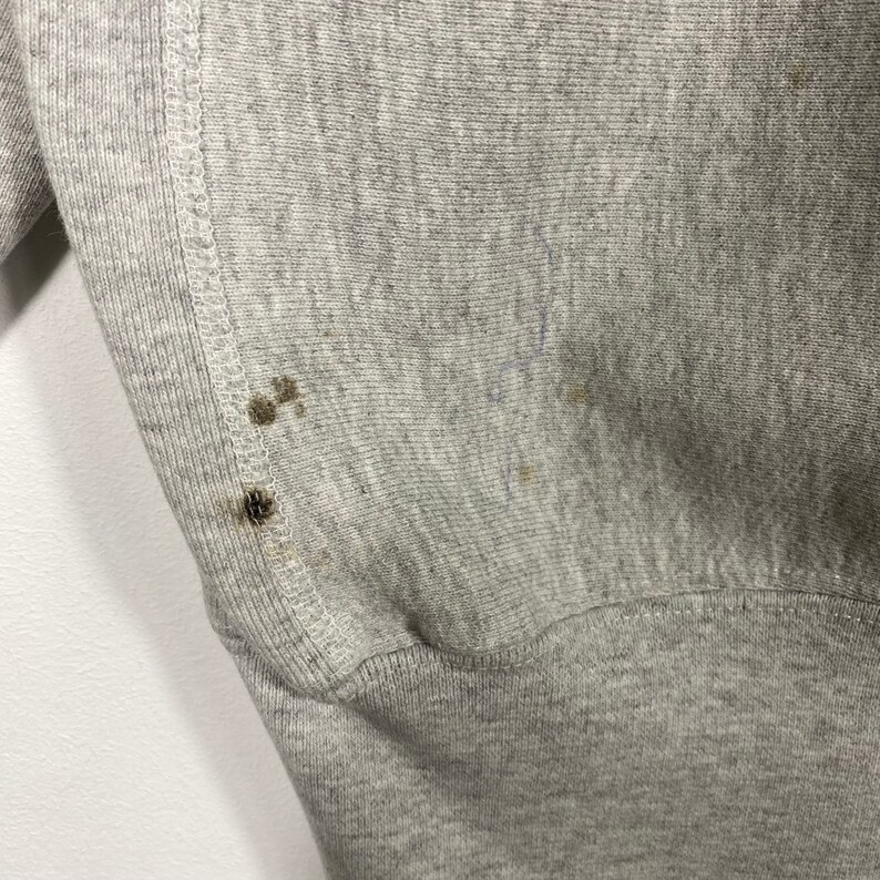 May include: Gray sweatshirt with a ribbed hem and a few small brown stains.