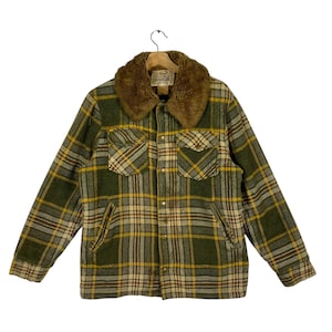 May include: A green, yellow, and brown plaid jacket with a brown faux fur collar. The jacket has two chest pockets and two side pockets. The jacket is hanging on a wooden hanger.