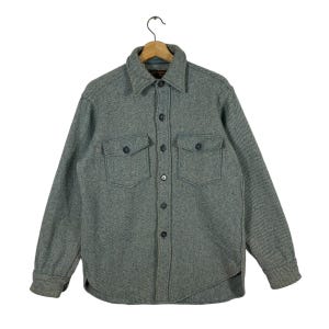 May include: A green and white striped long-sleeved shirt with a button-up front and two large pockets. The shirt has a classic, casual style.