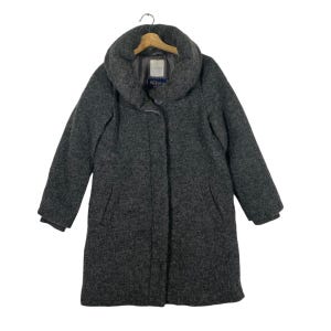 May include: A charcoal gray wool coat with a large, rounded collar. The coat has a single-button closure and two front pockets. The coat is hanging on a wooden hanger.