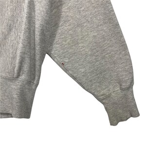 May include: Close-up of the gray sleeve of a sweatshirt with a small red stain.
