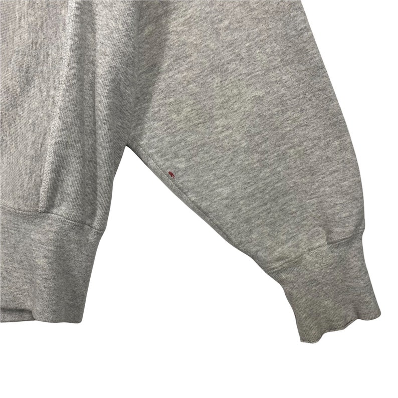 May include: Close-up of the gray sleeve of a sweatshirt with a small red stain.