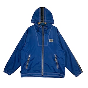 May include: A vibrant blue hooded jacket with a full-length zipper and white stitching details. The jacket features a logo patch on the chest and black accents on the hood and sleeves. Two zippered pockets are visible.