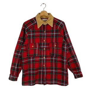 Puede incluir: Camisa de franela a cuadros rojos y negros con cuello de pana marrón. La camisa tiene dos bolsillos grandes en la parte delantera y cierre de botones.