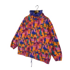 May include: A vintage fleece pullover with a colorful geometric pattern featuring ducks and trees. The fleece is a bright pink, orange, blue, and green. The pullover has a high neck and a drawstring at the bottom.