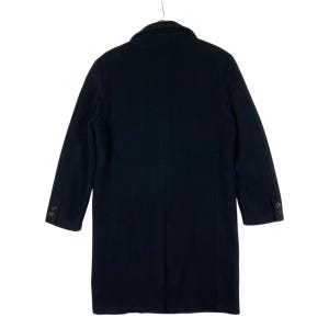 Pu&ograve; includere: Un cappotto nero dal design classico, visto da dietro. Il cappotto presenta un revers a lancia, maniche lunghe e due bottoni su ogni polsino. Il cappotto &egrave; appeso a una gruccia su sfondo bianco.