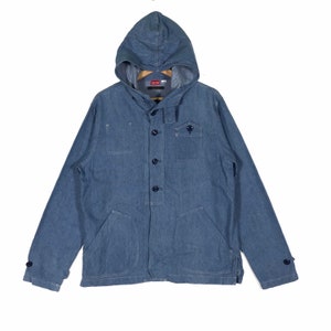 May include: A blue denim jacket with a hood and button closure. The jacket has two large pockets on the front and a smaller pocket on the chest. The jacket has a navy blue lining.