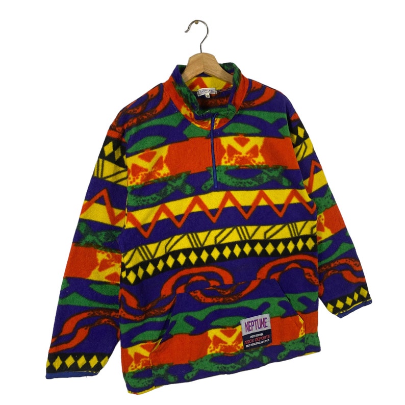 Puede incluir: Un jersey de forro polar multicolor con cierre de cremallera de media longitud. El jersey presenta un patr&oacute;n geom&eacute;trico en tonos rojos, amarillos, verdes, azules y negros. La etiqueta de la marca dice "NEPTUNE".