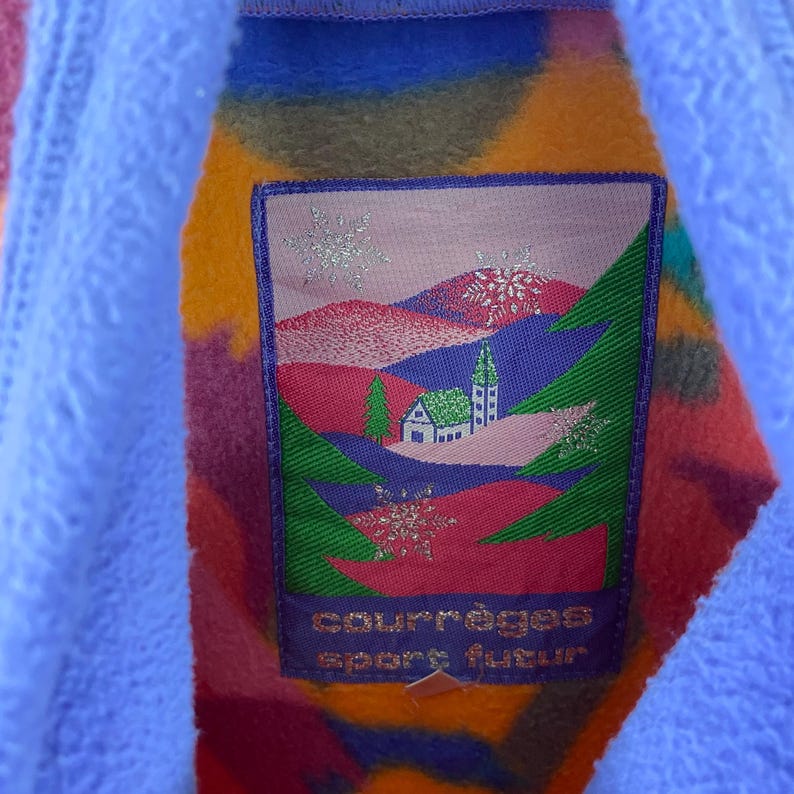 May include: A colorful fleece jacket with a patch featuring a winter scene with a small house and the text "Courr&egrave;ges Sport Futur".