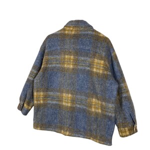 May include: A blue and gold plaid jacket with a button-down front and long sleeves. The jacket has a soft, textured appearance and a classic, oversized fit. The plaid pattern features a mix of blue and gold hues.