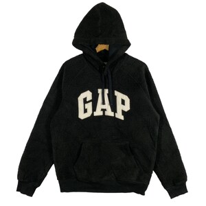 Pode incluir: Moletom preto com capuz com a palavra "GAP" em letras grandes e brancas no peito. O moletom tem um bolso canguru e um capuz com cordão. O material parece ser um tecido macio e texturizado.