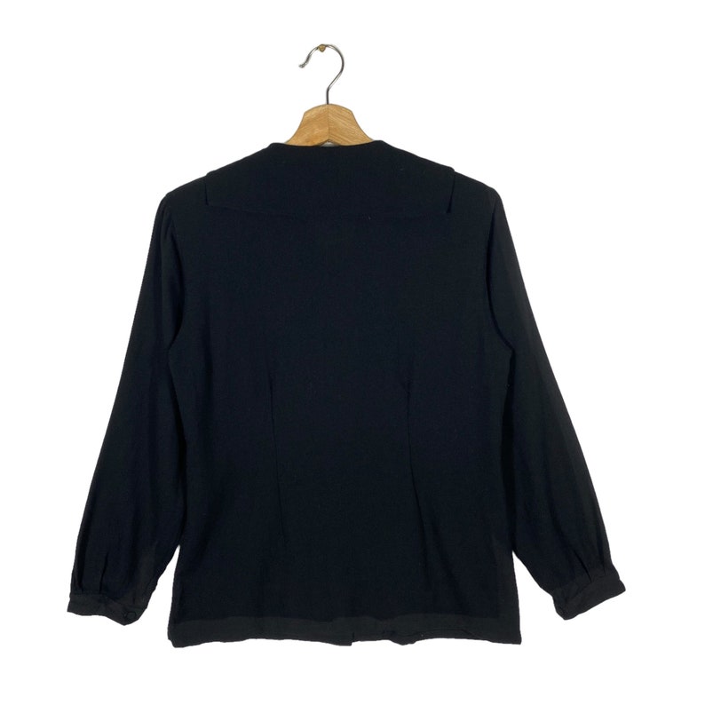 Puede incluir: Una blusa negra de manga larga con cuello alto y silueta ajustada.