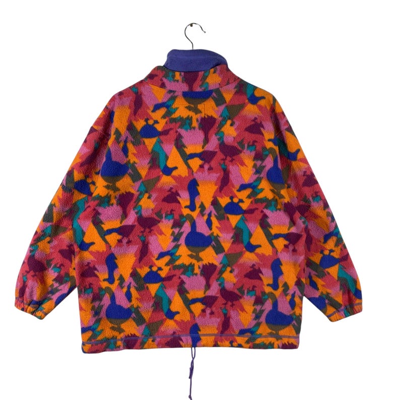 May include: A colorful fleece jacket with a geometric pattern of birds and triangles in shades of orange, pink, green, blue, and purple. The jacket has a high neck and a zipper closure.
