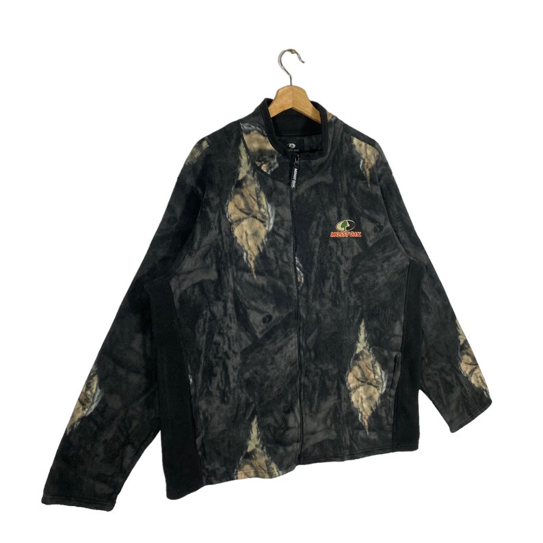 May include: A black and green camouflage fleece jacket with a zipper closure and a Mossy Oak logo on the front.