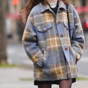 May include: A blue and yellow plaid jacket with a button-up front, two chest pockets, and two side pockets. The jacket has a relaxed fit and is made of a soft, textured fabric. The jacket is a stylish outerwear piece.