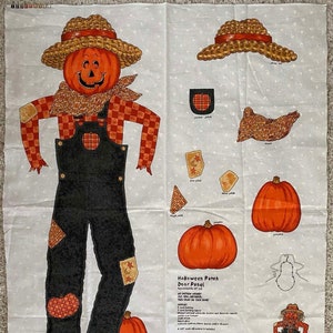 May include: A Halloween Patch Door Panel fabric with a scarecrow design. The scarecrow has an orange pumpkin head, a straw hat, and black overalls. Additional pumpkin and patch designs are included.